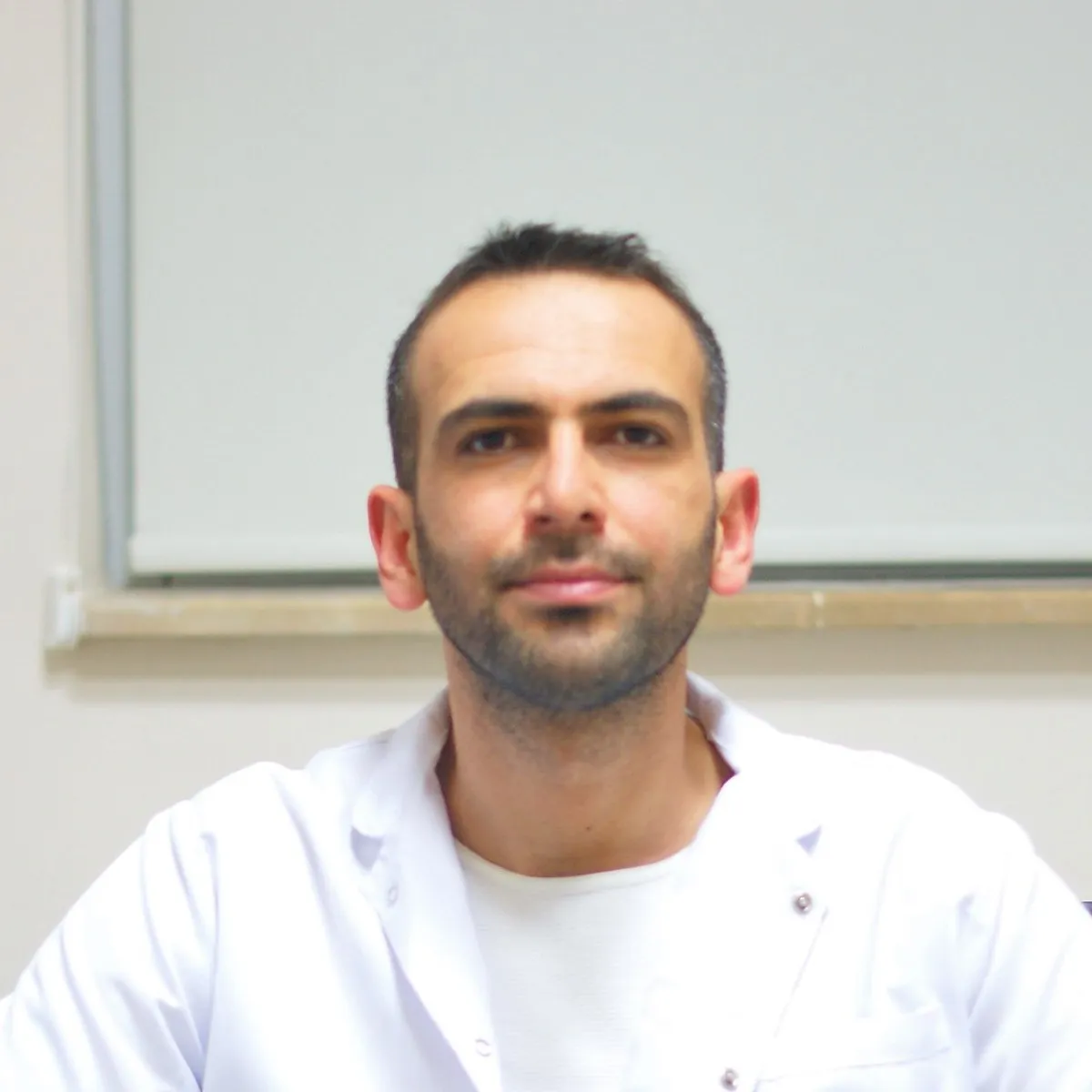 Cahit Örek, beyaz laboratuvar önlüğüyle masasında